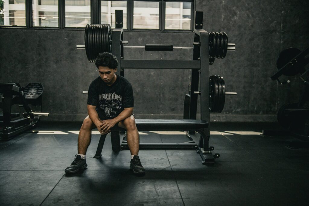 悩んでいる表情でジムウェアを着た男性