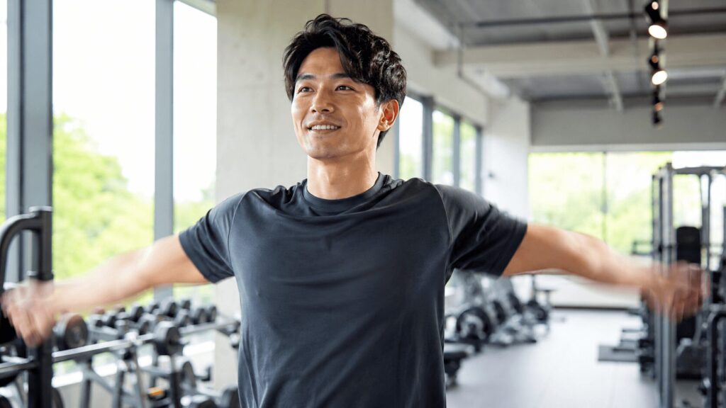 トレーニング前に肩を回してウォームアップする男性