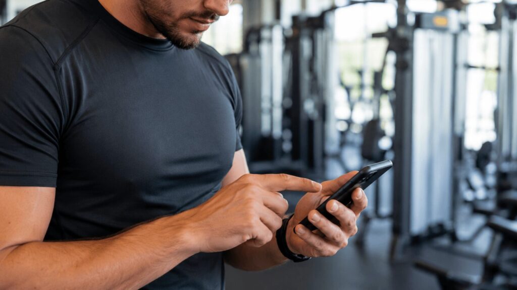 トレーニング記録をスマートフォンにメモする男性の手元