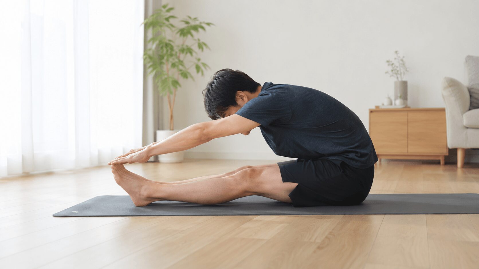トレーニング後にハムストリングスを伸ばす前屈ストレッチを行う男性