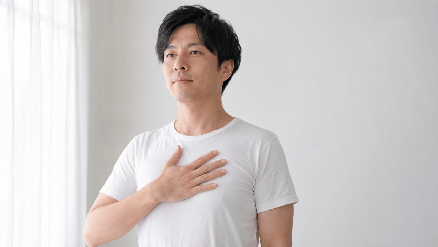 胸に手を当てて胸式呼吸を確認している30代男性と、お腹に手を当てて腹式呼吸を確認している対比の写真