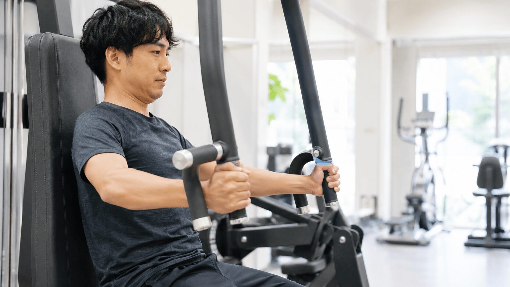 運動初心者の男性がジムでトレーニングマシンを使う様子