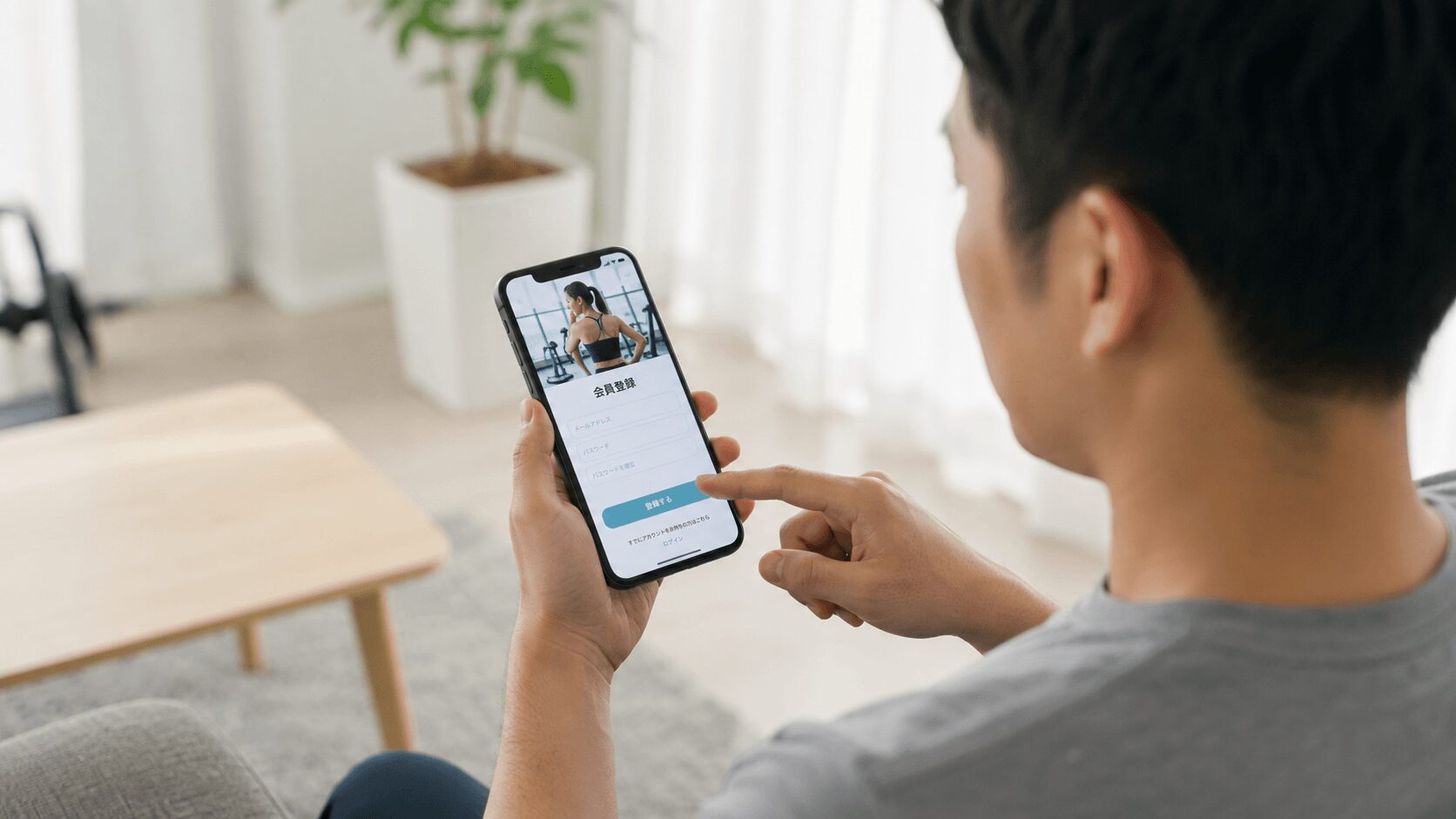 スマートフォンでジムの会員登録アプリを操作する男性