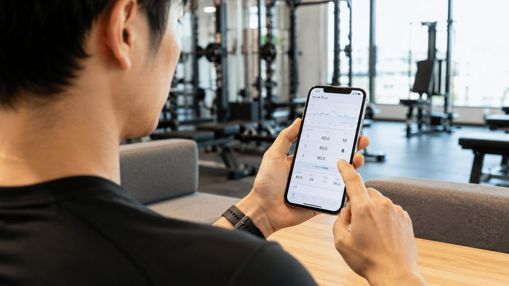 スマートフォンのトレーニング記録アプリを操作する男性