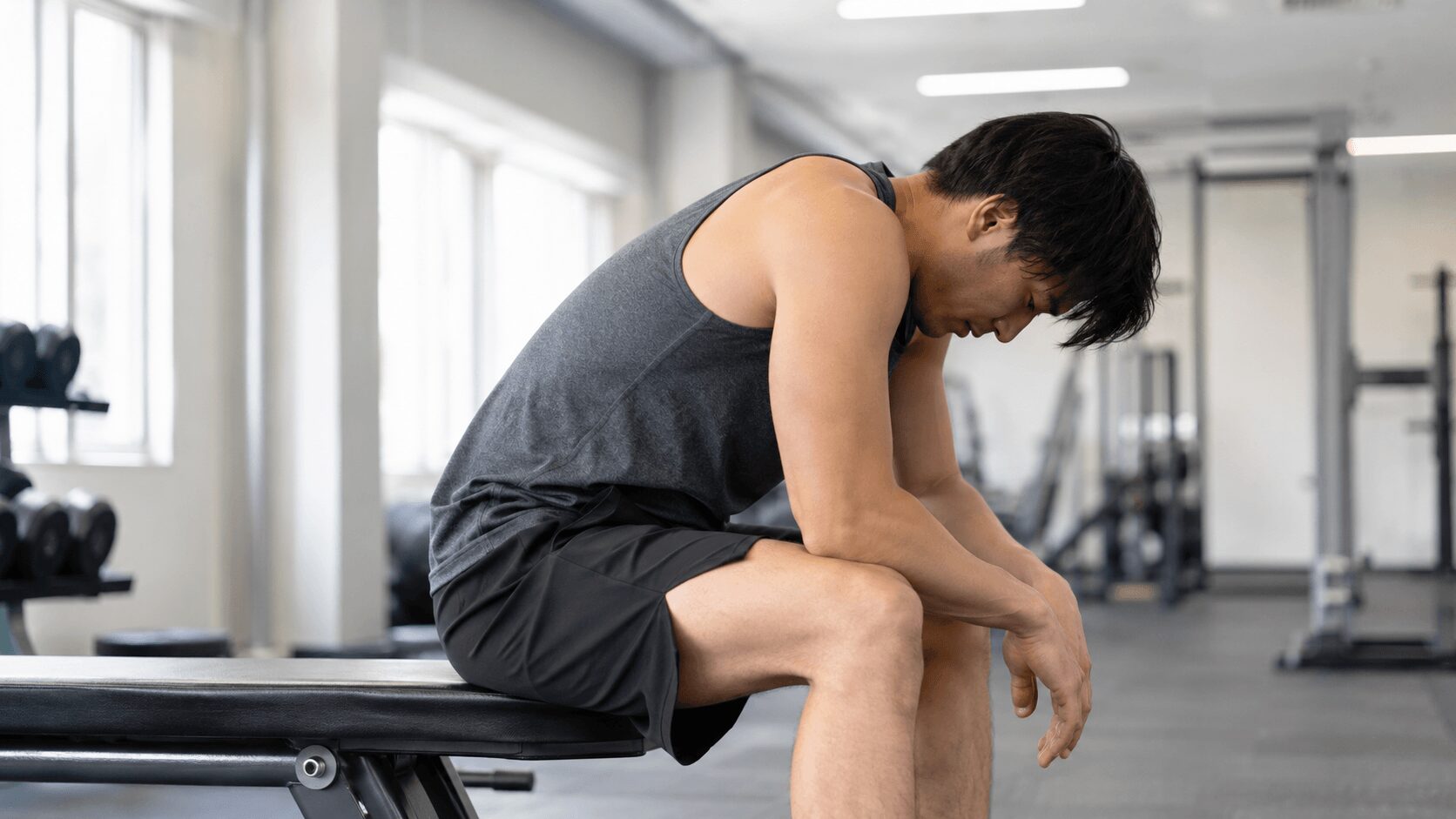 トレーニングで疲れ切りベンチに座り込む男性 筋トレがメンタルに逆効果になる例